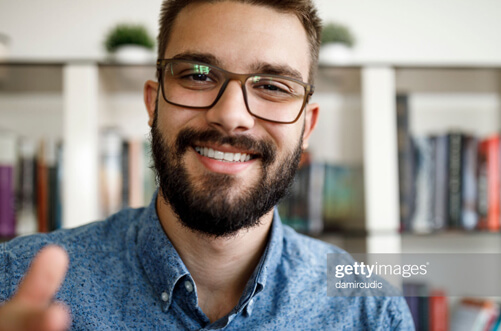 smiling man with glasses and beard in his home